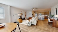 This thoughtfully designed 2-bedroom, 1-bathroom residence offers a comfortable and functional single-floor layout with a cohesive modern aesthetic. The open-concept living and kitchen area forms the heart of the home, with light wood-style flooring flowing throughout and connecting each space seamlessly. The living room is bright and inviting, featuring a ceiling fan and neutral tones that complement the warm, contemporary furnishings.

The kitchen is a standout, boasting warm taupe cabinetry extending to the ceiling for ample storage, stainless steel appliances, a white tile backsplash, and crisp quartz countertops. A central island with an undermount sink and seating for two adds both functionality and style, with elegant pendant lighting overhead.

Both bedrooms are carpeted for comfort and include ceiling fans and windows that invite natural light. The primary bedroom offers a generous footprint with room for a full furniture suite. A dedicated closet provides convenient storage.

The full bathroom features wood-look tile flooring, a double-drawer vanity with a white countertop, and a tub-shower combination with full tile surround and brushed nickel fixtures. A dedicated laundry area and utility room with a water heater round out the practical amenities of this well-appointed residence.
