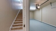 This two-floor residence offers a thoughtfully designed layout with a blend of practical and comfortable living spaces. The attached garage provides direct interior access via a carpeted staircase, featuring a smooth epoxy-coated floor, a motorized garage door opener, and ample clearance for vehicle storage.

The main living level showcases warm hardwood flooring and elegant crown molding throughout. The kitchen is equipped with white cabinetry, black appliances including a refrigerator, range, and built-in microwave, and a peninsula with a light stone countertop and stainless steel sink. This peninsula opens directly to the living and dining area, which features plush neutral carpeting and seamless flow between spaces.

The bedrooms are carpeted and finished with crown molding, offering a calm and comfortable atmosphere. The primary bedroom is generously sized with multiple windows that invite natural light and include a ceiling fan for added comfort. Additional bedrooms are well-proportioned with six-panel doors and clean neutral walls.

The bathroom features a white vanity with stone countertop, an undermount sink, polished chrome fixtures, a large framed mirror with vanity lighting above, and hardwood flooring. Throughout the home, warm beige tones, white trim, and consistent finishes create a cohesive and inviting ambiance.