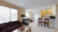 Located at 3025 Fountain Dr. in Beavercreek, Ohio, this single-floor residence offers a well-designed layout with a warm, neutral color palette and crown molding throughout. The open-concept living area is anchored by a standout two-sided fireplace, seamlessly connecting the living and dining spaces. Large windows invite abundant natural light, and a glass-top coffee table complements the comfortable seating arrangement. A dedicated dining nook features a bay window configuration that frames pleasant outdoor views, creating an inviting space for meals and gatherings. The galley-style kitchen is equipped with light wood cabinetry, ample counter space, and white appliances, offering an efficient and practical cooking environment. A breakfast bar provides additional seating and connects the kitchen to the main living area. The residence includes multiple bedrooms, each featuring plush carpeting, ceiling fans, crown molding, and generous closet space. The primary bedroom offers a serene retreat with access to an en-suite bathroom complete with a single-sink vanity and a glass-enclosed shower. A second full bathroom with a tub-shower combo and single-sink vanity serves the remaining bedrooms. Throughout the home, consistent finishes and thoughtful details create a cohesive and comfortable living environment.