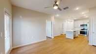 Located at Bay Island Lane in Kissimmee, Florida, this single-floor, one-bedroom, one-bathroom residence offers a well-designed layout with a cohesive modern aesthetic throughout. The open-concept kitchen and living area serves as the heart of the home, featuring crisp white shaker-style cabinetry that extends to the ceiling for maximum storage, bright white quartz countertops, stainless steel appliances including a French door refrigerator and range, and a central island with a built-in sink and pendant lighting above. Warm-toned wood-look flooring flows seamlessly through every room, creating a sense of continuity and warmth. The living area is bright and airy, with large windows fitted with blinds allowing natural light to fill the space, complemented by a ceiling fan overhead and direct access to an outdoor balcony. The bedroom offers a comfortable, well-proportioned retreat with dual windows overlooking greenery and an adjoining walk-in closet equipped with wire shelving. The bathroom is finished in neutral tones with a white vanity, quartz countertop, full soaking tub with shower, and wood-look flooring. Clean lines, neutral wall tones, and consistent finishes give the entire residence a fresh, move-in-ready feel.