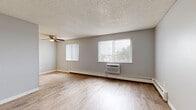 Located at 7100 Hooker St in Westminster, CO, this two-bedroom, one-bathroom unit offers a practical and comfortable single-floor layout. The living room is a bright, open space featuring light-toned luxury vinyl plank flooring, a textured ceiling, a ceiling fan, and dual windows dressed with vertical blinds that invite generous natural light and outdoor views. Baseboard heating and a wall-mounted A/C unit provide year-round climate control throughout the main living area.

The kitchen is efficiently designed with white cabinetry, dark countertops, a double-basin sink, and black appliances including an electric range and full-size refrigerator, all set atop easy-care LVP flooring. The galley-style layout maximizes storage and workspace within a compact footprint.

Both bedrooms feature plush carpeting, ceiling fans, baseboard heating, and vertical-blind windows. The spacious primary bedroom includes a sliding-door closet and direct access to the bathroom, which is equipped with a vanity and mirror. The second bedroom offers its own window and closet storage. Neutral gray walls throughout lend a clean, cohesive aesthetic, making this a straightforward and functional Westminster residence.