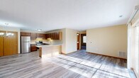 Located at 630 N Spring St in Port Washington, Wisconsin, this single-floor, two-bedroom, two-bathroom residence offers a practical and comfortable layout. The open-concept kitchen and living area serves as the heart of the home, featuring light hardwood-style luxury vinyl plank flooring that flows throughout the main living spaces. The kitchen is equipped with rich medium-toned wood cabinetry, stainless steel appliances including a refrigerator and gas range, a breakfast bar peninsula, and an overhead range hood. Natural light pours into the living area through large sliding glass patio doors that provide outdoor views and direct exterior access. Both bedrooms are carpeted and generously sized, with the primary bedroom offering ample closet storage and natural light through a wide window. The two bathrooms are finished with warm wood vanities, white countertops, and LVP flooring; one includes a full tub-shower combo. A dedicated laundry room adds everyday convenience. Warm neutral wall tones and wood-trimmed doors and baseboards carry a cohesive, welcoming aesthetic throughout the entire home.