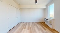 Located at 9749 SW Barber St in Wilsonville, Oregon, this efficiently designed studio offers a thoughtful layout that maximizes every square foot. Light wood-tone flooring runs throughout the entire unit, creating a warm and cohesive aesthetic. The open-concept kitchen and living area serves as the heart of the space, featuring a well-appointed kitchen with two-tone cabinetry in grey and dark wood finishes, white countertops, open shelving, and a full suite of black appliances including a refrigerator, electric range, microwave, and dishwasher. Recessed lighting illuminates the kitchen, while a French door leads directly to a private balcony overlooking a pleasant outdoor view — filling the living area with natural light. The bedroom area is clean and understated, with crisp white walls, a closet, and a wall-mounted heating unit. The bathroom is modern and stylish, showcasing a warm wood-grain vanity with white countertop, an illuminated LED-backlit mirror, and light hardwood-style flooring. Additional storage is provided through multiple closets throughout the unit. The overall ambiance is clean, contemporary, and move-in ready.