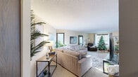 This single-floor residence offers a thoughtfully organized layout across several distinct living spaces. The living room serves as the heart of the home, featuring plush carpeting, textured ceilings, and multiple windows that draw in generous natural light while framing views of surrounding greenery. The open feel of the space is enhanced by its generous proportions, accommodating ample seating and additional accent furnishings.

Adjacent to the living room, the dining area features rich hardwood-style flooring, a sliding glass door providing direct access to an outdoor balcony, and a ceiling-mounted light fixture. The kitchen is equipped with dark cabinetry, a double-basin sink, granite-look countertops, a dishwasher, and a classic white subway tile backsplash.

The primary bedroom offers carpeted flooring, a ceiling fan, a large window with views of mature trees, and wall-to-wall closet space. A second bedroom also features carpet and full-height wood-paneled sliding closet doors. The bathroom includes a wide vanity with a single-basin sink, a large mirror, and overhead lighting, with hardwood-style flooring visible in the adjacent hallway.