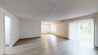 Located at 14260 SW 112th Ave in Tigard, Oregon, this single-floor, three-bedroom, one-bathroom home offers a practical and well-organized layout. The open living room is a standout feature, finished with light wood-style vinyl flooring, neutral walls, and a textured ceiling. Large vertical-blind-covered windows and a sliding glass door flood the space with natural light and provide views of the surrounding greenery. A step-down area within the living room adds a subtle architectural detail to the otherwise clean design.

The galley-style kitchen runs along two walls and is outfitted with warm wood-tone cabinetry, grey laminate countertops, a stainless steel sink, and white appliances including a range and refrigerator. Light vinyl flooring and overhead lighting keep the kitchen bright and functional.

All three bedrooms feature plush carpeting and textured ceilings. Each room is served by vertical-blind windows that bring in natural light, and the bedrooms include access to two closets for storage. The primary bedroom offers a comfortable footprint with ample wall space.

The single full bathroom is cleanly appointed with a tub-shower combination, a single-sink vanity with wood-tone cabinetry, a toilet, and vinyl flooring. The overall design of the home is clean, neutral, and move-in ready.