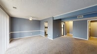 Located at 600 Country Club Dr in New Albany, Indiana, this single-floor residence offers a well-designed layout with a consistent cool-toned color palette of blue-gray walls, white trim, and textured ceilings throughout. The open living area is generously sized, featuring plush carpeting, a ceiling fan, and a seamless connection to the kitchen — making it an ideal space for both relaxing and entertaining. The kitchen is outfitted with white cabinetry, white countertops, stainless steel appliances including a refrigerator, electric range, and dishwasher, as well as a double-basin sink and wood-look flooring. Multiple carpeted bedrooms provide comfortable living quarters, each painted in coordinating shades of blue-gray and featuring windows with blinds that allow natural light. The primary bathroom includes a soaking tub, a walk-in glass-door shower, a white vanity, and wood-look tile flooring. A second bathroom offers a tub-shower combination with similar flooring. Additional features include a walk-in closet with built-in shelving adjacent to the primary bath, ample storage throughout, and a cohesive modern aesthetic that ties the entire space together.