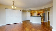 Located at 525 S Burdick St in Kalamazoo, Michigan, this single-floor residence offers a thoughtfully designed layout with a cohesive blend of modern finishes and functional living spaces. The open-concept living and dining area is anchored by warm hardwood flooring that reflects natural light from multiple windows fitted with vertical blinds. An elegant chandelier adds a refined touch overhead, while a set of large bifold closet doors provides generous built-in storage. The kitchen flows seamlessly from the living area via a curved breakfast bar with dark granite countertops. Honey-toned wood cabinetry pairs with a full suite of stainless steel appliances—including a refrigerator, range, microwave, and dishwasher—while light ceramic tile flooring ties the space together. The bedroom features plush carpeting, a spacious walk-in closet with wire shelving, and a serene, neutral palette. Two well-appointed bathrooms echo the kitchen's design language, each showcasing dark granite countertops, undermount sinks, and warm wood vanities. One bathroom includes a tub-shower combination, while the other offers a dedicated shower. Throughout, textured ceilings, clean white baseboards, and a consistent warm color scheme create a welcoming and practical living environment.