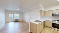 Located at 11603 NE 71st St in Vancouver, WA, this thoughtfully designed 2-bedroom, 1-bathroom residence offers a clean, contemporary aesthetic throughout its single-floor layout. The open-concept kitchen and living area serves as the heart of the home, featuring light wood-tone cabinetry, white quartz-style countertops, stainless steel appliances including a gas range, microwave, refrigerator, and dishwasher, and a peninsula that provides additional workspace and casual dining potential. Light hardwood flooring runs throughout the main living areas, enhancing the bright, airy feel of the space. The primary bedroom offers direct access to a private balcony through a glass door, paired with a wall-unit climate control system and generous natural light. The second bedroom is finished with plush carpet and features dual windows that bring in abundant daylight. Three closets provide ample storage, including a carpeted walk-in closet with wire shelving. The full bathroom is finished with wood-toned cabinetry, a white countertop vanity, a large mirror, and a soaking tub with shower. A dedicated laundry area adds everyday convenience. Clean white walls and consistent modern finishes give this residence a fresh, move-in-ready character throughout.