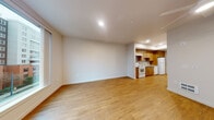 Located at 2065 South River Parkway in Portland, Oregon, Unit 330 is a thoughtfully designed single-floor residence that combines practical functionality with clean, modern aesthetics. Warm-toned hardwood-style flooring flows throughout the main living areas, creating a cohesive and inviting atmosphere.

The kitchen is a standout feature, outfitted with rich wood cabinetry extending to the ceiling for ample storage, light quartz-style countertops, and a full suite of white appliances including a range, dishwasher, and refrigerator. A stainless steel sink and under-cabinet range hood complete the well-appointed space.

The open living area is generously proportioned, bathed in natural light from a large picture window that frames views of the surrounding Portland cityscape. Recessed lighting and a ceiling fan with integrated light fixture add comfort and versatility to the space.

A built-in closet with shelving provides convenient storage directly off the main living area. The bathroom features a wood-toned vanity with drawers, a mirror, and neutral tile flooring, maintaining the consistent design language found throughout the unit.

The entryway includes a keypad-secured door and an electrical panel access point, adding both security and practicality. Overall, the unit presents a clean, move-in-ready environment with a cohesive warm-toned palette.