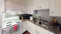 This single-floor, 2-bedroom, 1-bathroom residence offers a well-organized layout that maximizes its footprint with practical, comfortable living spaces. Warm-toned hardwood floors run throughout the home, lending a consistent and inviting character to every room.

The living area is bright and open, with a ceiling fan overhead and a window that allows natural light to fill the space. It connects directly to the kitchen, creating an easy flow between entertaining and cooking areas. The kitchen is thoughtfully appointed with white cabinetry, dark countertops, a stainless steel double-basin sink, and a standout embossed metallic tile backsplash that adds visual interest and a touch of character.

Both bedrooms are comfortably sized, each featuring hardwood floors, ceiling fans with light fixtures, and windows fitted with blinds that offer natural light and privacy. One bedroom includes a louvered closet door, adding functional storage.

The bathroom is efficiently laid out with a vanity counter, a large mirror, and a separate water closet area housing the toilet and a tub-shower combination. Clean white walls and dark hardwood floors give the bathroom a crisp, functional finish. Overall, the home presents a clean, straightforward aesthetic with consistent finishes throughout.