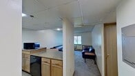 Located at 646 East College Avenue in State College, PA, this 560-square-foot, one-bedroom, one-bathroom apartment offers a practical and functional layout across a single floor. The living room features wall-to-wall carpeting, a window with vertical blinds overlooking a green outdoor area, and a wall-mounted HVAC unit providing individual climate control. The kitchen is equipped with hardwood-style flooring, granite-look countertops, wood cabinetry, a full-size refrigerator, a dishwasher, and dedicated counter space for small appliances. The bedroom spans 170 square feet and includes carpeted flooring, a large window with vertical blinds, a wall-mounted HVAC unit, and an open built-in closet with multiple shelving rods for organized storage. The bathroom features a large wall mirror, a vanity sink, and a toilet. A hallway and closet round out the unit's layout. Throughout the apartment, tile-panel ceilings provide a uniform finish. The ground-floor location offers easy access, and the outdoor-facing windows in both the living room and bedroom bring in natural light and views of the surrounding landscaping.