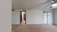 This well-organized single-floor unit offers 1 bedroom, 2 bathrooms, and a thoughtful layout that maximizes every square foot. The living room serves as the heart of the home, featuring warm neutral carpet, a ceiling fan with light fixture, a large window, and a sliding glass door fitted with vertical blinds that opens to an outdoor area — allowing natural light to fill the space. A hallway connects the living area to the remaining rooms, framed by dark-trimmed doorways that add a subtle contrast to the light walls.

The combined kitchen and dining area features warm wood-toned cabinetry, laminate countertops, a double sink, and white appliances including a refrigerator and dishwasher. Wood-look flooring grounds the kitchen, which transitions seamlessly into the adjoining dining space.

The bedroom is carpeted and well-lit, with a ceiling fan and a window offering outdoor views. It also includes access to a closet for convenient storage. An additional room serves as a flexible office space, also carpeted and equipped with a ceiling fan.

Both bathrooms are functional and consistent in design, each featuring wood-toned vanity cabinetry, a single-basin sink with laminate countertops, a mirror, and a tub/shower combination with tile surround. Wood-look flooring completes the bathroom aesthetic.