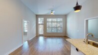 Located at 611 Daniels St in Raleigh, NC, this single-floor residence showcases a contemporary design with an open-concept layout that promotes a sense of spaciousness and easy flow between living areas. The main living space features warm hardwood-style flooring, soaring ceilings, and a ceiling fan, while an expansive multi-pane window and a glass-paneled door flood the room with natural light and offer views of surrounding greenery. A ceiling fan adds both function and style to the airy living area.

The kitchen is a standout feature, boasting tall white upper cabinetry paired with dark lower cabinets, stainless steel appliances including a refrigerator, range, and microwave, and a granite-topped island with an undermount sink. Stylish pendant lighting and a track light fixture add a modern touch, while an in-unit laundry area is conveniently accessible nearby.

The bedroom features plush carpeting, neutral walls, and a window that brings in natural light. The bathrooms are finished with granite countertops, dark wood vanity cabinetry, hardwood-style tile flooring, and a tub-shower combination. Throughout the unit, a neutral color palette and clean lines create a cohesive, modern ambiance.