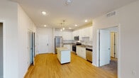 This single-floor residence offers a thoughtfully designed open-concept layout that seamlessly connects the kitchen and living areas. The kitchen serves as the heart of the home, showcasing crisp white shaker cabinetry, granite countertops, a full suite of stainless steel appliances including a refrigerator, electric range, microwave, and dishwasher, along with a central island with additional counter space. Stylish pendant lighting adds a refined touch above the island. Light hardwood-style flooring runs throughout the main living and kitchen areas, creating a warm, cohesive aesthetic. The living area benefits from natural light courtesy of multiple windows with blinds. Bedrooms are finished with plush carpeting and feature generous windows that bring in outdoor views. The bathrooms are well-appointed with granite-topped vanities, undermount sinks, and walk-in closet access, with one bathroom offering a shower/tub combination. A dedicated in-unit laundry closet equipped with a front-loading washer adds everyday convenience. The space also includes a private entry door and ample storage throughout, making it a complete and functional residence.
