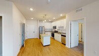 This single-floor residence offers a thoughtfully designed open-concept layout that seamlessly connects the kitchen and living areas. The kitchen serves as the heart of the home, showcasing crisp white shaker cabinetry, granite countertops, a full suite of stainless steel appliances including a refrigerator, electric range, microwave, and dishwasher, along with a central island with additional counter space. Stylish pendant lighting adds a refined touch above the island. Light hardwood-style flooring runs throughout the main living and kitchen areas, creating a warm, cohesive aesthetic. The living area benefits from natural light courtesy of multiple windows with blinds. Bedrooms are finished with plush carpeting and feature generous windows that bring in outdoor views. The bathrooms are well-appointed with granite-topped vanities, undermount sinks, and walk-in closet access, with one bathroom offering a shower/tub combination. A dedicated in-unit laundry closet equipped with a front-loading washer adds everyday convenience. The space also includes a private entry door and ample storage throughout, making it a complete and functional residence.