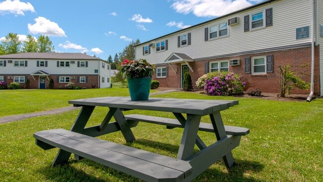 Elevate your outdoor gatherings at one of our inviting picnic tables, where blue skies and lush landscapes set the stage for memorable moments with friends. - Aspen Chase Apartments