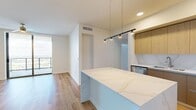 Located along Tampa's scenic Riverwalk Trail, this modern 4-bedroom, 3-bathroom residence offers a thoughtfully designed open-concept layout with high-end finishes throughout. The kitchen and living area form a seamless central hub, anchored by a striking marble-veined quartz island with pendant lighting overhead. The kitchen features flat-panel wood cabinetry, a matching quartz backsplash, stainless steel appliances including a built-in oven, microwave, and French door refrigerator, all set atop warm hardwood-style flooring. Bedrooms are generously proportioned, with select rooms showcasing plush carpeting, ceiling fans, and dramatic floor-to-ceiling windows that frame sweeping views of the waterfront and Tampa skyline. One bedroom opens directly to a private balcony through sliding glass doors, flooding the space with natural light. The bathrooms are finished in a clean, contemporary style, with one featuring a full soaking tub surrounded by marble-style tile surround and wood-look flooring. Carpeted hallways connect the bedrooms, maintaining a quiet, residential feel. Throughout, the design emphasizes clean lines, neutral tones, and natural light, creating a bright and cohesive living environment in one of Tampa's most vibrant urban neighborhoods.