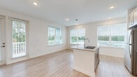 Located at 550 Webb Gin House Rd in Lawrenceville, GA, this single-floor residence offers a bright, modern design with a clean, neutral palette throughout. The open-concept living and kitchen area is anchored by a central island with granite countertops, an undermount sink, and stainless steel appliances, including a range, microwave, and dishwasher. Gray shaker-style cabinetry and recessed lighting complete the kitchen's polished aesthetic. Light wood-look flooring runs through the main living areas, creating a seamless flow from the kitchen into the spacious living room, which is lined with multiple windows offering views of the landscaped grounds and surrounding greenery. The bedrooms feature plush carpeting, ceiling fans, and generous window placements that invite natural light and outdoor views. The primary bathroom is equipped with a dual-sink vanity topped with granite, gray cabinetry, and a large mirror with overhead lighting. A well-appointed hallway connects the rooms efficiently, with a built-in utility panel adding a practical touch. The outdoor balcony overlooks a thoughtfully landscaped community with mature trees and winding drives, providing a tranquil setting in Gwinnett County.