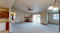 Located at 1951 Scheuring Rd in De Pere, Wisconsin, this single-floor, 2-bedroom, 2-bathroom home offers a well-organized layout with a comfortable and functional design throughout. The living room serves as the centerpiece of the home, featuring vaulted ceilings, a corner fireplace with a tile surround and wood mantel, a ceiling fan, and sliding glass doors that open to an outdoor deck, inviting natural light and outdoor views into the space. Baseboard heating is found throughout, complementing the carpeted floors that run through the living areas and bedrooms. The kitchen is efficiently designed with warm oak cabinetry, light countertops, tile flooring, and a full suite of appliances including a refrigerator, range, microwave, and dishwasher. A dining area adjacent to the kitchen features a decorative pendant light fixture. The two bedrooms are generously sized, each with carpet, natural light from windows with outdoor views, and baseboard heating. The primary bedroom offers ample space and closet access. Both bathrooms are finished with tile flooring and oak vanity cabinetry; one includes a tub-shower combination. A hallway and closet complete the thoughtful floor plan of this inviting home.