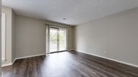 Located at 7929 Sycamore Ave in Kansas City, MO, this two-bedroom, one-bathroom single-floor home offers a practical and well-appointed layout. The living area features dark hardwood-style flooring, neutral warm-toned walls, a textured ceiling, and a ceiling fan. A sliding glass door leads to a private balcony, filling the space with natural light and offering pleasant outdoor views of surrounding greenery. The galley-style kitchen is efficiently designed with white shaker cabinetry, granite-look countertops, a deep single-basin sink with a matte black faucet, and black appliances including a range, microwave, and refrigerator — all set atop light wood-look flooring. The primary bedroom is a comfortable, well-sized room with plush carpet, a window for natural light, and access to a dedicated closet with built-in shelving. The second bedroom is similarly carpeted and bright, with a window fitted with blinds. The bathroom includes a white vanity with under-cabinet storage, a white countertop, matte black fixtures, and a mirror above the sink. A hallway connects the rooms, providing a clean and functional flow throughout the home. The consistent use of neutral tones and updated finishes creates a cohesive and move-in-ready atmosphere.