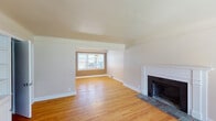 This three-floor home offers a well-organized layout with a variety of functional and comfortable living spaces. The main living area is a standout, featuring warm hardwood flooring, crisp white trim, and a classic wood-burning fireplace with a tile hearth and a neatly detailed white mantel surround. A windowed dining nook at the far end of the room allows natural light to filter in, complemented by a small chandelier overhead, creating a bright and inviting atmosphere.

The bedrooms are carpeted and each includes a ceiling fan with integrated lighting, providing comfort and airflow. Windows in each room invite natural light and outdoor views, lending a pleasant, airy quality to the private spaces.

The kitchen is equipped with warm oak cabinetry, dark laminate countertops, and includes a dishwasher, offering practical functionality. The tile flooring in this area adds durability and easy maintenance.

The bathroom features classic white subway tile wainscoting, slate-toned floor tiles, a white vanity with medicine cabinet, and a window for natural ventilation and light.

The basement level houses the mechanical systems, including the HVAC ductwork, furnace, and water heater, and features a clean concrete floor, offering additional utility and storage potential throughout this multi-story home.