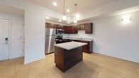 Located at 505 W 7th St in New Castle, Delaware, this single-floor residence offers a thoughtfully designed layout that combines modern finishes with functional living spaces. The open-concept kitchen serves as the heart of the home, showcasing rich dark-wood cabinetry, granite countertops, a central island with pendant lighting overhead, and a full suite of stainless steel appliances including a refrigerator, range, and microwave. Light wood-style flooring flows throughout the kitchen and living areas, lending warmth and continuity to the open floor plan. The living area is bright and welcoming, benefiting from natural light that pours in through sliding glass doors that open onto a private balcony, offering an outdoor retreat. The bedroom features plush carpeting, a generously sized closet, and a window that fills the room with natural light. A carpeted hallway connects the bedroom to additional storage and the full bathroom, which is finished with large-format tile flooring, a tiled tub-surround, a soaking tub, and a dual-sink vanity topped with granite. The corridor area also reveals a walk-in closet with built-in shelving. Throughout the residence, clean white walls, recessed lighting, and consistent high-quality finishes create a cohesive and move-in-ready atmosphere.