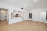 Located at 9940 Robbins Dr in Beverly Hills, this thoughtfully designed one-bedroom, one-bathroom residence offers a clean, modern aesthetic throughout. Light-toned hardwood flooring flows seamlessly across the entire space, complementing a crisp all-white palette that enhances the sense of openness and brightness.

The combined kitchen and living area serves as the heart of the home. The living room features striking vaulted, arched ceilings with recessed lighting, multiple windows, and a glass sliding door that opens to a private balcony overlooking lush greenery. The kitchen is well-appointed with white shaker cabinetry, marble-look countertops, a neutral tile backsplash, and a full suite of stainless steel appliances including a gas range, dishwasher, built-in microwave, and refrigerator.

The bedroom is a bright, tranquil retreat with two windows framing views of the surrounding trees. It includes a built-in closet with organized shelving and drawers, offering practical storage. A second closet provides additional space.

The bathroom is elegantly finished, featuring a glass-enclosed walk-in shower clad in vertical gray tile, hexagonal mosaic floor tile, a built-in bench, and a small window for natural light. Two hallways connect the spaces efficiently, completing this polished Beverly Hills residence.