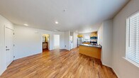Located at 1402 E 69th St in Tacoma, WA, this one-bedroom, one-bathroom unit offers a practical and well-appointed layout across a single floor. The open-concept kitchen and living area serves as the heart of the unit, featuring warm wood-tone cabinetry, a peninsula with a dark countertop and double sink, and a full suite of stainless steel appliances including a refrigerator, electric range, and over-the-range microwave. Hardwood-style flooring runs throughout the kitchen and living area, adding warmth and continuity. A stacked washer and dryer is conveniently tucked into the unit, providing in-unit laundry. Multiple windows with horizontal blinds allow natural light to filter into the space and offer views of surrounding greenery. The bedroom is carpeted for comfort and includes a closet and a window that brings in additional natural light. The bathroom features a wood-toned vanity with a dark countertop, a wall-mounted mirror with lighting, and a tub-shower combination, all complemented by hardwood-style flooring. Clean white walls and recessed lighting throughout contribute to a bright, neutral aesthetic that is easy to personalize.