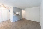 Located at 9030 Betel Dr in El Paso, Texas, this single-floor unit offers a functional and well-organized layout designed for comfortable everyday living. The living area is carpeted and bathed in natural light from a large sliding glass door that opens to a balcony, complemented by a ceiling fan overhead and a textured ceiling throughout. A bold gray accent wall with a pass-through window connects the living space to the kitchen, which features a galley-style design with light wood-look vinyl flooring, gray cabinetry, mosaic tile backsplash, white appliances including a range and refrigerator, a stainless steel sink, and a dishwasher. The bedrooms are carpeted and bright, each with windows dressed in horizontal blinds that allow natural light while maintaining privacy. One area includes a dedicated vanity space with a built-in countertop, a drawer unit, and a well-lit mirror, along with adjacent wire shelving for added storage. The bathroom is clean and efficiently laid out, featuring a tub-shower combination with tile surround, a single-sink vanity with a speckled countertop, and wood-look vinyl flooring. Throughout the unit, the neutral color palette and practical finishes create a cohesive and move-in-ready environment.