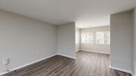Located at 4048 Battleground Ave in Greensboro, NC, this single-floor, one-bedroom, one-bathroom unit offers a well-organized layout across a comfortable footprint. The open-concept main area seamlessly combines the living room, dining room, and kitchen, creating a versatile space for everyday living and entertaining. The kitchen is outfitted with white cabinetry, granite-style countertops, and a full suite of stainless steel appliances including a range, microwave, dishwasher, and refrigerator. Wood-style hard flooring runs throughout the main living areas, adding warmth and easy maintenance. Natural light filters in through multiple windows dressed with white blinds, brightening the neutral gray-toned walls. A dedicated den provides additional flexible space for a home office or secondary sitting area. The bedroom features plush carpeting, a ceiling fan, a window with outdoor views, and access to a closet with built-in shelving. The bathroom includes a full tub/shower combination. A separate laundry room is equipped with washer and dryer hookups, adding everyday convenience. A hallway connects the private areas of the unit efficiently, completing this functional and well-appointed residential space.