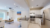 This thoughtfully designed unit at The Miriam in Memphis, Tennessee, offers a bright, open floor plan that maximizes its compact footprint. The kitchen serves as a central focal point, featuring white shaker cabinetry, a white subway tile backsplash, dark granite countertops, stainless steel appliances, and a peninsula with bar seating — ideal for casual dining and entertaining. The kitchen flows seamlessly into the living area, which is finished with glossy white tile flooring, recessed lighting, and a ceiling fan, creating a clean, modern aesthetic throughout the shared space.

The primary bedroom is generously proportioned, finished with plush carpet, crown molding, a ceiling fan, and a sliding glass door that opens to an outdoor area, allowing natural light to fill the room. The second bedroom offers comfortable carpeted space with neutral walls, well-suited as a guest room or home office. The single bathroom is elegantly appointed with marble-style tile surrounding a full tub-shower combination with a sliding glass enclosure, lending a refined, upscale feel. Throughout the unit, the consistent use of neutral tones and modern finishes contributes to a cohesive, contemporary ambiance.