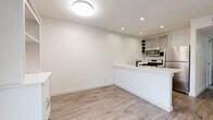This thoughtfully designed 2-bedroom, 2-bathroom single-floor residence offers a clean, modern aesthetic with an efficient and functional layout. Light-toned wood-look flooring flows seamlessly throughout the entire space, creating a cohesive and airy feel.

The open-concept living and kitchen area serves as the heart of the home. The kitchen features a peninsula with a white quartz countertop, stainless steel appliances including a gas range, built-in microwave, and refrigerator, complemented by gray cabinetry with open shelving and a classic subway tile backsplash. Recessed lighting illuminates the space, which connects naturally to the living area anchored by a modern entry door with frosted glass panel inserts and a large window that invites natural light.

The primary bedroom offers a comfortable footprint with a ceiling fan, a sliding closet with built-in wire shelving, and a private door leading outdoors. The second bedroom is also generously sized with a ceiling fan and outdoor access through a glass door. Each bathroom is well-appointed with a gray vanity, white basin sink, and matte black fixtures. One bathroom conveniently houses an in-unit washer. A hallway and dedicated closet provide additional storage throughout.