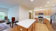 Located on the fourth floor at 3020 University Ave SE in Minneapolis, this thoughtfully laid-out one-bedroom, one-bathroom unit offers a comfortable and functional living environment. The open-concept living room features warm hardwood flooring, large sliding glass doors leading to a private balcony, and abundant natural light framed by lush tree views — creating an inviting, airy atmosphere. The well-appointed kitchen includes warm-toned wood cabinetry extending to the ceiling, white countertops, stainless steel appliances including a dishwasher, microwave, and refrigerator, plus a central island for additional prep space. The bedroom is carpeted and bright, with a large sliding glass door opening to the balcony, a built-in closet with bifold doors, and direct access to the hallway. The full bathroom features tile flooring, a tub-shower combination, a wide vanity with ample cabinetry, and a large mirror. Two additional office spaces provide flexible options for remote work or storage — one with a window overlooking green surroundings. The hallway entry includes a built-in closet and connects seamlessly to all areas of the unit. Hardwood flooring flows throughout the main living areas, tying the space together with a clean, cohesive aesthetic.