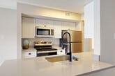 Located at 775 Gateway Dr SE in Leesburg, VA, this 2-bedroom, 3-bathroom single-floor residence offers a thoughtfully designed open-concept layout. The kitchen is a functional centerpiece, featuring white shaker cabinetry, stainless steel appliances including an electric range, over-the-range microwave, and refrigerator, complemented by light quartz countertops and a peninsula with bar seating and a matte black faucet. The living room is anchored by a classic wood-burning fireplace with a white mantel and tile surround, with light wood-style flooring flowing throughout the main areas. Large windows with horizontal blinds allow generous natural light into the adjacent dining area, which also benefits from access to an exterior door. Both bedrooms are carpeted and offer a calm, neutral palette; the primary bedroom includes a ceiling fan and ample space for full-sized furniture. Two of the three bathrooms feature tub-shower combinations with crisp white tile. Additional conveniences include a dedicated laundry area, two closets, and a hallway connecting the main rooms. The overall ambiance is bright, clean, and move-in ready.