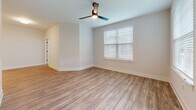 Located at 104 Herrings Green Loop in Mooresville, NC, this single-story, 2-bedroom, 2-bathroom home delivers a clean, modern aesthetic with a practical and comfortable layout. The open-concept kitchen and living area forms the heart of the home. The kitchen is outfitted with crisp white shaker cabinetry, stainless steel appliances, a center island with a built-in sink, white countertops, and stylish pendant lighting — all set atop light wood-tone luxury vinyl plank flooring. The living room flows naturally from the kitchen and is bathed in natural light through multiple windows, complemented by a sleek ceiling fan and direct access to the exterior via a glass-paneled door. The primary bedroom features wood-look LVP flooring, a ceiling fan, and a walk-in closet with built-in wire shelving for ample organization. The second bedroom offers plush carpeting, a ceiling fan, and its own walk-in closet with wire shelving. Both bathrooms are finished with white vanities, wood-tone LVP flooring, and matte black hardware accents. The guest bathroom includes a tiled tub-shower combination. Throughout the home, neutral tones, white panel doors, and consistent finishes create a cohesive and inviting atmosphere.