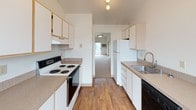 Located at 12202 East Maxwell Avenue in Spokane, Washington, this single-floor home offers a well-organized layout with comfortable living spaces throughout. The living room is a standout area, featuring soaring vaulted ceilings, soft carpeting, and a tile-surround fireplace that serves as a natural focal point. Pendant lighting adds warmth to the space, while a sliding glass door provides access to an outdoor balcony and fills the room with natural light. The galley-style kitchen is efficiently designed with white cabinetry, laminate countertops, hardwood-style flooring, a full suite of appliances including an electric range, dishwasher, and refrigerator, and track lighting overhead. The bedrooms are generously sized, each featuring vaulted ceilings, plush carpeting, large windows that invite natural light, and baseboard heating. The primary bedroom connects to a bathroom with a wide vanity, large mirror, and ample under-counter storage, along with an adjacent walk-in closet with built-in shelving. A full bathroom includes a tub/shower combination and hardwood-style flooring. A dedicated laundry area accommodates a full-sized washer and dryer with an overhead wood shelf for additional storage. This home offers a clean, functional design throughout.