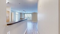 Located at 105 King Farm Blvd in Rockville, MD, this well-appointed 2-bedroom, 2-bathroom residence offers a thoughtfully designed single-floor layout. The open-concept kitchen and living area serve as the heart of the home, featuring light wood cabinetry, dark granite-style countertops, a breakfast bar peninsula, and black appliances including a gas range, microwave, and refrigerator. Light hardwood-style flooring flows seamlessly throughout the main living areas, complemented by crown molding and neutral warm-toned walls that create a bright, welcoming ambiance. Large windows in the living room flood the space with natural light and offer pleasant outdoor views of surrounding greenery. The primary bedroom is generously sized, featuring plush carpeting, a ceiling fan with light fixture, crown molding, and access to a spacious walk-in closet equipped with wire shelving. The second bedroom also offers comfortable proportions, soft carpeting, and a large window. Both bathrooms are finished with warm wood-toned vanities, white countertops, large mirrors with overhead lighting, and tile flooring. Two closets provide ample storage throughout the residence, rounding out a functional and comfortable living space.