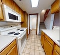 Located at 5608 W Memorial Rd in Oklahoma City, Oklahoma, this two-story property offers a practical and well-organized layout across both levels. The main floor features a galley-style kitchen equipped with warm oak cabinetry, white appliances including a range and over-the-range microwave, and light ceramic tile flooring. A convenient bathroom is accessible directly from the main level, positioned adjacent to the staircase. The living area on the main floor is carpeted and open, providing a versatile space suited for a variety of uses. A thermostat and smoke detector are visibly installed, reflecting attention to comfort and safety. Carpeted stairs connect the two floors, with an interior door providing access to additional utility or storage space on the lower level. The upper floor hosts multiple carpeted bedrooms, each featuring neutral white walls, wood-trimmed baseboards, and ceiling fans for added comfort. One bedroom includes a sliding-door closet, offering practical storage. The bathroom features a vanity with a wide mirror, a standard sink, and a toilet. Throughout the property, textured ceilings, neutral tones, and consistent wood trim detailing provide a cohesive and understated aesthetic.