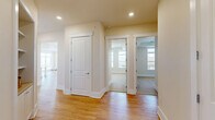 Located at 16408 Holly Crest Lane in Huntersville, NC, this well-appointed single-floor home offers three bedrooms and three bathrooms within a thoughtfully designed layout. The open-concept living, dining, and kitchen area serves as the heart of the home, showcasing warm hardwood flooring and an abundance of natural light through multiple windows. The kitchen is a standout feature, outfitted with floor-to-ceiling white cabinetry with glass-front upper panels, stainless steel appliances including a side-by-side refrigerator, double wall oven, and microwave, a classic subway tile backsplash, a wall-mounted range hood, and a peninsula with seating. The bedrooms are carpeted and generously sized, with the primary bedroom featuring a tray ceiling and built-in shelving. Each bathroom is finished with crisp white subway tile; one includes a spacious walk-in shower with mosaic tile flooring and a built-in bench, while another offers a soaking tub with tiled surround. The home includes six closets, a dedicated pantry, laundry room, utility room, hallways, and a balcony. Recessed lighting and ceiling fans throughout contribute to a bright, comfortable ambiance.