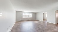 Located at 931 W Main St in New Britain, Connecticut, this single-floor unit presents a straightforward and functional layout designed for comfortable everyday living. Throughout the space, wood-style laminate flooring provides a cohesive and easy-to-maintain surface that runs seamlessly from room to room.

The living area is generously sized, featuring neutral gray walls, white trim, and large windows dressed with vertical blinds that allow natural light to filter in and cast bright patterns across the floor. Baseboard heating units line the walls, ensuring efficient warmth throughout the cooler months.

The kitchen is open and practical, outfitted with warm honey-toned wood cabinetry offering ample storage both above and below the counter. Stainless steel appliances, including a gas range and refrigerator, are paired with a single-basin sink and a ventilation hood, making the space well-equipped for daily use. The kitchen opens directly to the main living area, creating an accessible, connected flow.

The bedrooms are well-proportioned and bright, each featuring wood-style flooring, neutral walls, baseboard heating, and windows that provide natural light and outdoor views. The bathroom is cleanly finished with large-format gray tile flooring, a white vanity with mirrored medicine cabinet, and a bathtub, presenting a tidy and functional design.