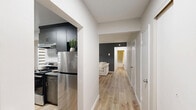 Located at 11405 132 St in Edmonton, AB, this well-appointed one-bedroom, one-bathroom unit offers a thoughtfully designed layout across a single floor. Light wood laminate flooring runs throughout, creating a warm and cohesive feel across all rooms.

The living room features a large window dressed with zebra blinds, a built-in baseboard heater, and a neutral grey and navy accent wall that adds depth and character to the space. An entryway area is accented by a decorative navy sideboard and arched gold-framed mirrors, setting an elegant tone upon entry.

The kitchen is efficiently laid out with dark wood-toned cabinetry, grey stone countertops, a tile backsplash, and stainless steel appliances including a refrigerator and electric range with a hood fan. A dedicated dining nook adjacent to the kitchen comfortably accommodates a full dining set beneath a bright window.

The bedroom is a standout feature, showcasing a striking slate-blue panel accent wall, a large zebra-blind window, and a ceiling light fixture, offering a cozy and refined retreat.

The bathroom is finished with marble-look tile surrounds in the combined tub and shower, complemented by chrome fixtures for a clean, polished look.

Hallways connect the rooms efficiently, and the overall interior palette of soft greys, warm wood, and blue accents lends the space a modern, cohesive aesthetic.