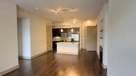 This single-floor residence in Dallas, TX, offers a thoughtfully designed open-concept layout that seamlessly connects the living and kitchen areas. Rich, dark hardwood floors extend throughout the main living space, adding warmth and sophistication to the interior.

The kitchen is a standout feature, showcasing dark espresso cabinetry that contrasts elegantly with light granite countertops on the central island. A subway tile backsplash adds a clean, modern touch, while stainless steel appliances — including a refrigerator and microwave — provide a sleek, functional aesthetic. Pendant lighting hangs above the island, complementing the track lighting overhead that illuminates the space with a warm, inviting glow.

The open living area is generously proportioned, offering flexible arrangement possibilities. Neutral-toned walls create a bright, airy atmosphere throughout. Additional doors visible from the main area suggest access to separate rooms or utility spaces, contributing to the home's practical layout.

A fireplace is partially visible at the edge of the living area, hinting at a cozy focal point for the space. Overall, this Dallas residence combines modern design elements with functional living, making it an appealing and well-appointed home.