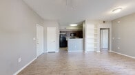Located at 1350 N Euless Main St in Euless, Texas, this one-bedroom, one-bathroom residence offers a well-designed single-floor layout that maximizes every square foot. The combined living and dining area is the heart of the home, characterized by soaring vaulted ceilings that create an airy, open feel. Wood-look plank flooring runs throughout, lending warmth and continuity to the space. A set of large windows along one wall floods the living area with natural light, while a built-in shelving unit adds functional display and storage space.

The galley-style kitchen is efficiently laid out with dark espresso cabinetry, granite-look countertops, a stainless steel sink, and black appliances including a range, microwave, and refrigerator. A peninsula counter separates the kitchen from the dining and living area, offering a convenient pass-through space.

The bedroom is a comfortable, well-proportioned room with wood-look flooring and ample closet access. The full bathroom features a dark-framed vanity mirror, granite countertop, dark wood cabinetry with brushed nickel hardware, and a shower-tub combination. A dedicated laundry area accommodates a full-size washer and dryer. Two closets and a hallway complete the efficient, functional floor plan of this Euless residence.