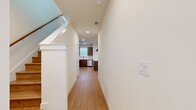 This two-story home offers a well-organized layout across two floors, with the main living areas on the lower level and the bedrooms situated above. The ground floor features an open-concept kitchen and living room, where light wood-tone flooring runs throughout, creating a warm, cohesive aesthetic. The kitchen is appointed with rich dark cabinetry, stainless steel appliances including a French door refrigerator, and stone countertops, all complemented by recessed lighting. A hallway connects the main living spaces and leads to a convenient half bath on this level.

Upstairs, the more expansive floor houses all three bedrooms, three closets, and the remaining bathrooms. The generously sized primary bedroom features dual windows with outdoor views, flooding the room with natural light, and includes a walk-in closet with built-in shelving and hanging rods. The secondary bedrooms are carpeted and each include a ceiling fan, a window with exterior views, and closet access. A dedicated laundry room on this floor is equipped with a washer and upper cabinetry for added storage. The bathrooms are clean and well-appointed with brushed nickel hardware. Two staircases provide convenient circulation between floors, and the overall design is characterized by crisp white walls, light hardwood flooring, and a bright, modern ambiance throughout.
