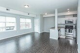 Located at 30333 Southfield Rd in Southfield, Michigan, this single-floor residence offers a clean, modern aesthetic with a thoughtfully designed layout. The open-concept living area features rich, dark hardwood-style flooring and neutral gray walls, creating a bright and versatile space. Large windows fitted with roller shades allow generous natural light to filter in while offering views of the surrounding community.

The kitchen is a standout feature, equipped with stainless steel appliances including a refrigerator with ice maker, electric range, and microwave. White cabinetry provides ample storage, while granite countertops extend across a peninsula-style breakfast bar that connects the kitchen to the living space, making it ideal for casual dining or entertaining.

The bedroom is carpeted for comfort and benefits from two generously sized windows that frame outdoor views and fill the room with natural light. A dedicated closet with built-in shelving and a hanging rod offers practical storage. The neutral tones throughout maintain a calm, cohesive ambiance.

The bathroom is finished with a granite-topped vanity, a tiled tub-and-shower combination featuring large-format wood-look tile surround, and warm, coordinated fixtures. Overall, this residence presents a contemporary and functional living environment with consistent, quality finishes from room to room.