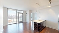 Located in Chicago's vibrant Lincoln Park neighborhood, this one-bedroom, one-bathroom residence at 1457 North Halsted Street offers a thoughtfully designed open-concept layout with modern finishes. Rich hardwood flooring flows throughout the main living areas, anchoring the space with warmth and continuity.

The kitchen serves as a focal point of the home, featuring a large island with a built-in sink, wine rack, and light countertops that contrast beautifully with the deep espresso-toned cabinetry. Stainless steel appliances — including a gas range, microwave, and refrigerator — complement the contemporary aesthetic. Pendant and track lighting illuminate the space with both style and function.

The open living area benefits from expansive floor-to-ceiling windows and a glass door that frame striking views of the Chicago skyline, flooding the room with natural light. The bedroom continues the hardwood flooring and includes a window with additional city views, offering a bright and airy retreat.

The hallway provides access to an in-unit stacked washer and dryer closet — a highly practical feature. The bathroom is finished with clean white tile flooring and crisp white walls, maintaining the unit's clean, modern aesthetic throughout. A dedicated closet rounds out the functional layout of this well-appointed urban residence.