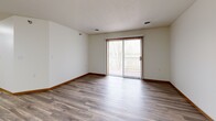 This 1-bedroom, 1-bathroom unit at 2750 S 38th St in Grand Forks, ND offers a practical and comfortable layout across a single floor. The open-concept kitchen and living area serves as the heart of the unit, featuring wood-look plank flooring throughout. The kitchen is well-equipped with white cabinetry, light countertops, a full suite of stainless steel appliances including a refrigerator, range, microwave, and dishwasher, and a center island that provides additional prep space and storage. The living room is bright and open, highlighted by a sliding glass patio door with vertical blinds that allows natural light to fill the space and provides outdoor access. The bedroom offers a comfortable, carpeted retreat with a dedicated closet featuring warm wood-toned doors, a natural light source via a framed window, and direct access to the bathroom. The full bathroom is clean and functional, featuring a tub/shower combination with chrome fixtures and wood-look tile flooring. Warm wood baseboards throughout the unit add a cohesive finishing touch. The overall aesthetic is clean, neutral, and move-in ready, making it a functional and efficient living space.