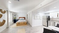 Located at 1000 Navaho Dr in Raleigh, NC, this efficiently designed one-bedroom, one-bathroom unit offers a thoughtfully organized single-floor layout that maximizes every square foot. Light wood-look flooring flows consistently throughout the space, creating a clean and cohesive aesthetic anchored by bright white walls and trim.

The bedroom is generously proportioned, occupying a significant portion of the floor plan. It features a large window with curtains that allow natural light to fill the room, along with a sliding closet door providing practical storage. The open sightlines from the bedroom connect directly to the kitchen and entry areas, reinforcing the unit's open feel.

The kitchen is a standout feature, equipped with white shaker-style cabinetry, granite countertops, a stainless steel refrigerator, dishwasher, and range, as well as a microwave. A skylight overhead floods the kitchen with natural light, enhancing the crisp, modern aesthetic. A small dining area adjacent to the kitchen accommodates a table and chairs.

The bathroom continues the clean design language with white cabinetry, granite countertops, a framed mirror, and matte black fixtures. The space is compact yet well-appointed.

Throughout the unit, recessed lighting and ceiling vents ensure comfort, while the consistent use of light tones and minimal architectural detailing gives the space a bright, airy ambiance.