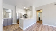 Located at 700 N Coronado St in Chandler, Arizona, this single-story, one-bedroom, one-bathroom unit offers a well-designed layout across a comfortable floor plan. Light wood-look flooring runs throughout, complementing the clean, neutral color palette found in every room.

The open-concept kitchen is a standout feature, equipped with stainless steel appliances including a refrigerator, microwave, and range. White upper cabinetry pairs with gray lower cabinets and bright white quartz countertops, while a peninsula island provides additional prep and seating space.

The living room is bright and airy, featuring a ceiling fan and a sliding glass door that opens to an outdoor patio, allowing ample natural light and outdoor views to flow into the space.

The bedroom is generously sized with a ceiling fan, wood-look flooring, and direct access to a walk-in closet outfitted with multi-tiered shelving and hanging rods for organized storage.

The bathroom features a gray vanity with a white quartz countertop, dual sinks with brushed nickel fixtures, a large mirror, and a full soaking tub-shower combination.

A dedicated laundry area with a full-size washer and dryer adds everyday convenience, completing this thoughtfully appointed home.