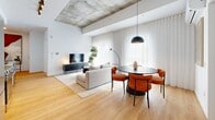 Located at 5630 Rue De Marseille in Montréal, this thoughtfully designed one-bedroom, one-bathroom unit offers a clean, modern aesthetic across a single floor. The open-concept living and dining area is a standout space, distinguished by striking exposed concrete ceiling elements that contrast beautifully against crisp white walls and warm light hardwood flooring. Sheer floor-to-ceiling curtains filter natural light generously throughout, creating a bright and airy ambiance. The living area comfortably accommodates both a lounge and dining arrangement, anchored by a bold pendant light above a sleek round dining table. A dedicated office space provides a functional work-from-home area, complete with natural light and an exposed concrete column that adds an industrial touch. The bedroom is a serene retreat, featuring large windows dressed in sheer curtains that bathe the room in soft light, complemented by light hardwood floors and clean white walls. The bathroom is elegantly finished with warm wood cabinetry, open shelving, beige tile flooring, and a full bathtub with a glass shower partition. A clean, linear hallway with recessed lighting and a sliding door connects the rooms seamlessly, reinforcing the unit's cohesive and contemporary design throughout.